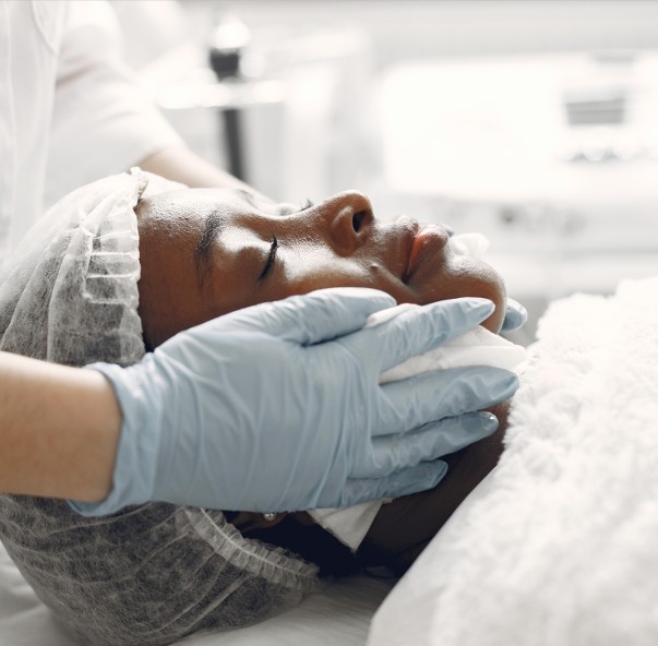 A gloved practitioner gently supporting a client's face during a skin treatment