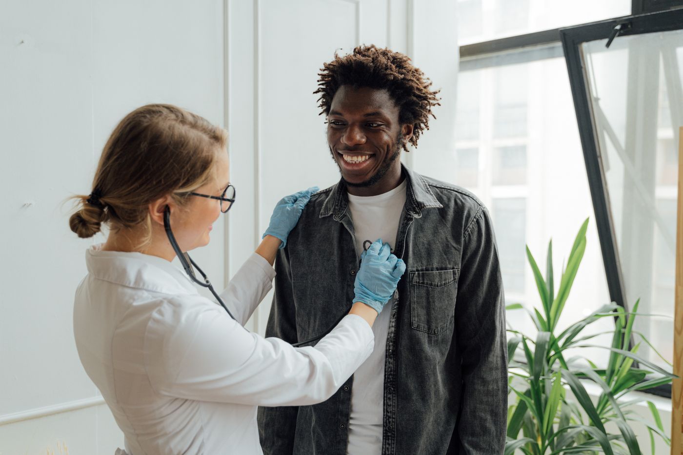 A doctor listening to a smiling patient’s chest with a stethoscope